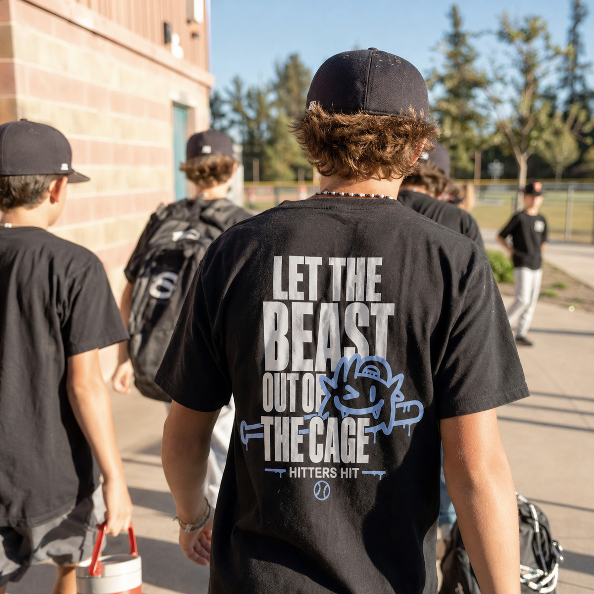 Teen walking at a baseball field in a black Beast adult T-shirt with back graphic.