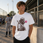 Teen wearing the white Bigfoot Bubble adult baseball T-shirt at a baseball complex with the large front graphic and pink bubble visible.