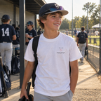 Youth baseball player wearing a white Built for the Game Glove T-shirt with the small TB 03 Glove System left-chest graphic at a baseball field.